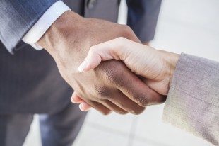 African American businessman or man shaking hands with a businesswoman or woman caucasian female colleague making a business deal