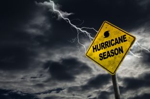 Hurricane season with symbol sign against a stormy background and copy space. Dirty and angled sign adds to the drama.